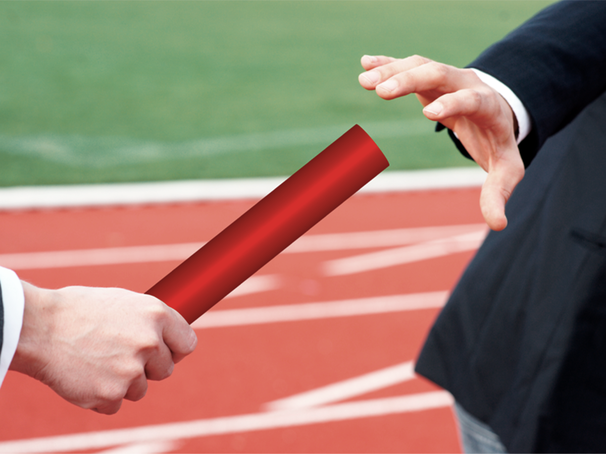 Change of baton with racetrack in the background