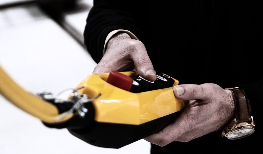 Close-up of two male hands on a typical yellow industrial remote control